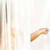 woman standing at shower and holding hands under water